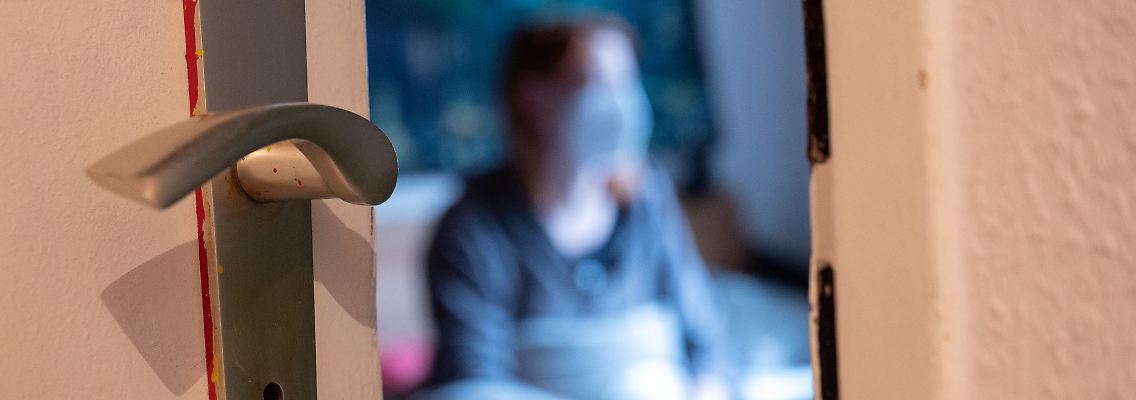 Eine Frau sitzt während der Isolation nach einem positiven Corona-PCR-Test auf ihrem Bett.