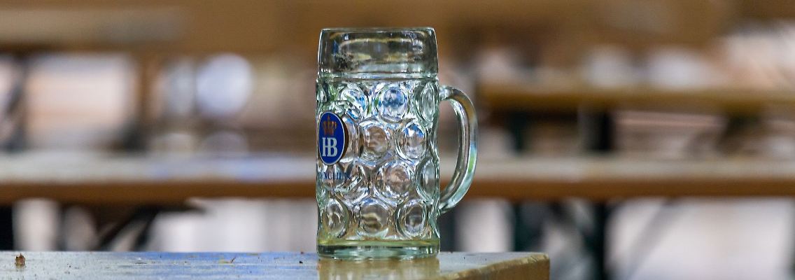 Ein leerer Bierkrug steht auf einem Tisch in einem verregnetem Biergarten.