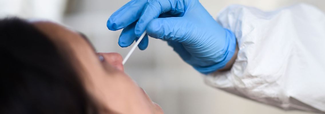 Eine Mitarbeiterin eines Testzentrums entnimmt einer Frau einen Nasenabstrich für einen Corona-Test.