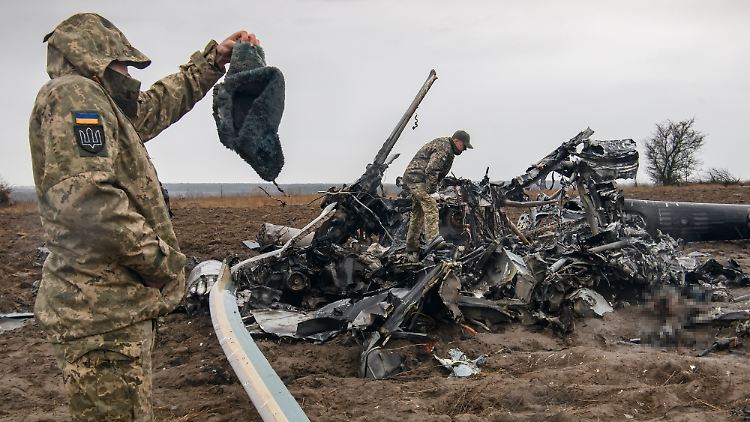 Ukrainische Soldaten untersuchen einen abgeschossenen russischen Hubschrauber.