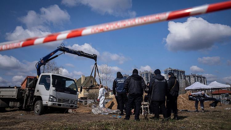 Gerichtsmediziner und Polizisten untersuchen Leichen aus einem Massengrab in Butscha.