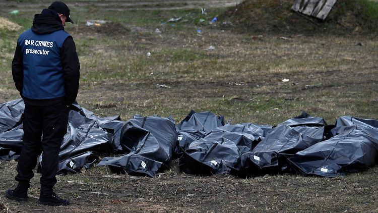 Ein ukrainischer Ermittler betrachtet aus einem Massengrab in Butscha exhumierte Leichname.