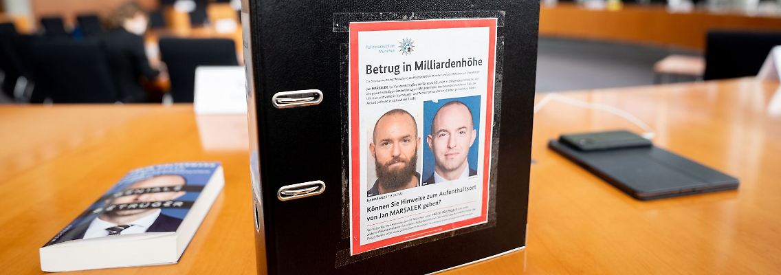 Ein Aktenordner mit Fahndungsfotos von Jan Marsalek im Untersuchungsausschuss des Bundestags. Ist der frühere Wirecard-Vorstand in Russland?