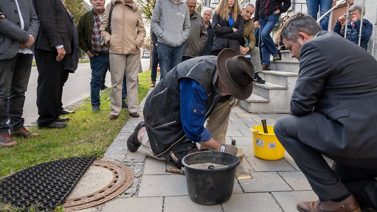 Der Künstler Gunter Demnig verlegt zwei Stolpersteine vor einem Haus in Penzberg.