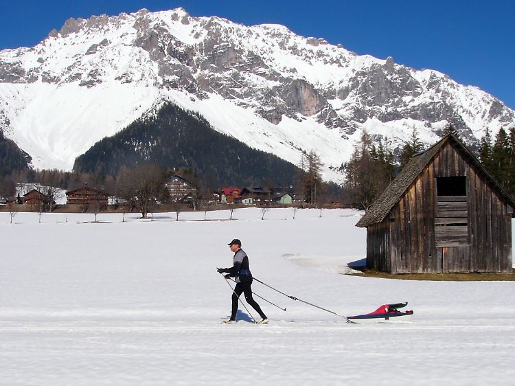 Baby an Bord: Ein Langläufer zieht seinen Nachwuchs durch die Winterwelt der Ramsau.