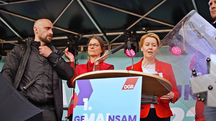 Giffey wird nach der Eier-Attacke mit Schild und Schirm geschützt.