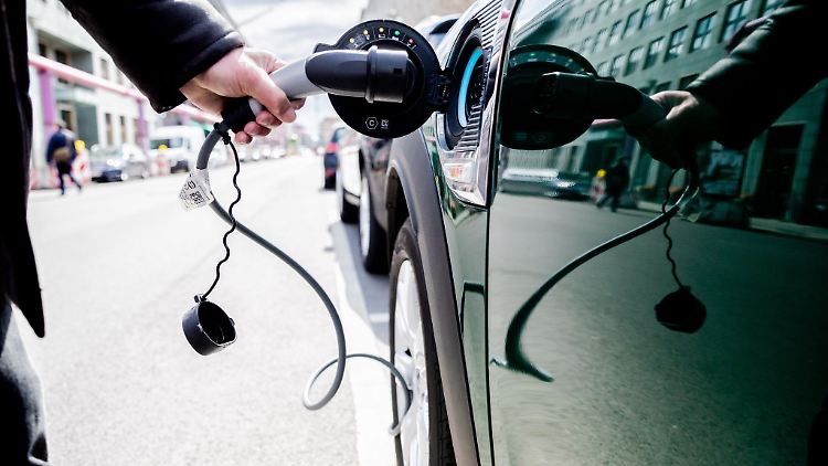Ein Mann entfernt den Stecker an einem Auto mit Plug-in-Hybrid-Antrieb.