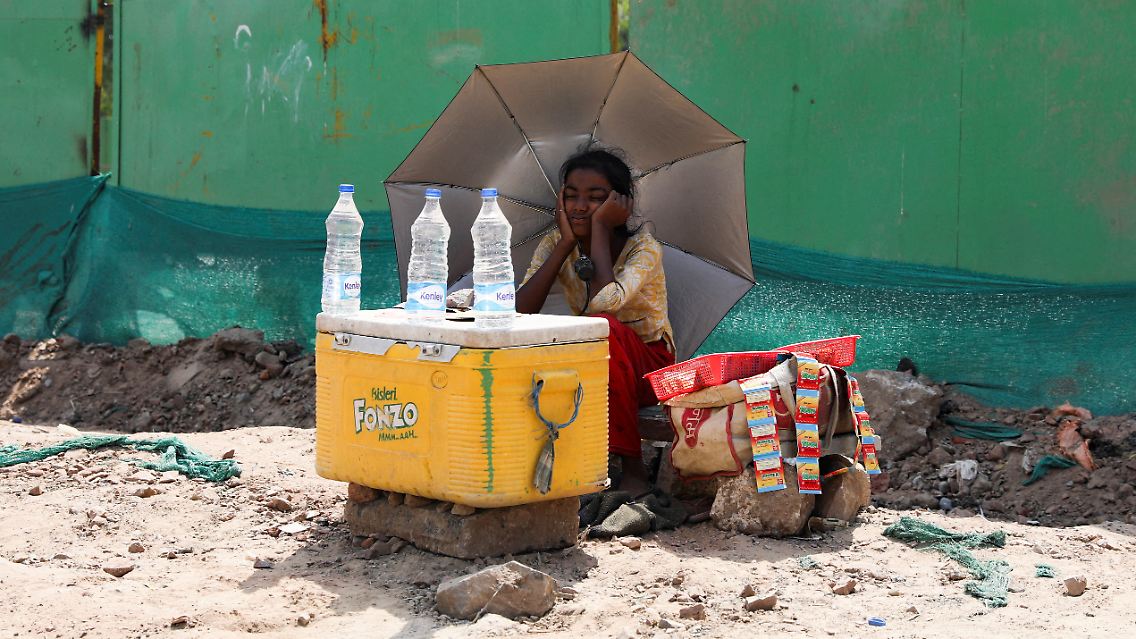 In Neu Delhi trinken schwitzende Passantinnen und Passanten immer wieder Wasser, das sie an kleinen Ständen überall in der Stadt kaufen.