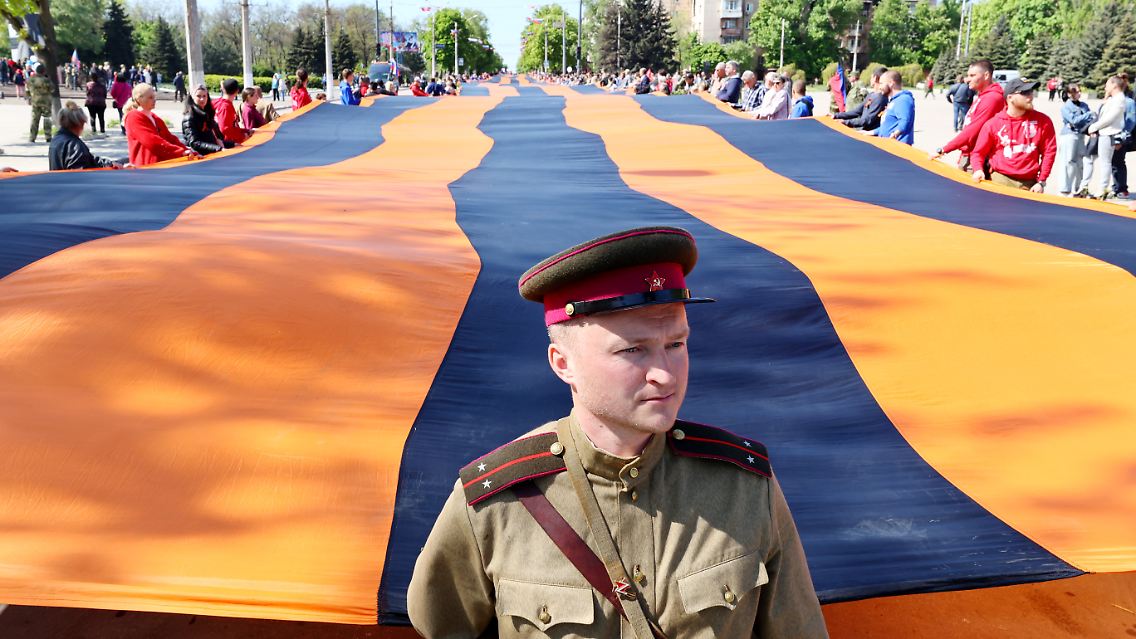 Ein riesiges Sankt-Georgsband wird durch die Ruinen von Mariupol getragen.