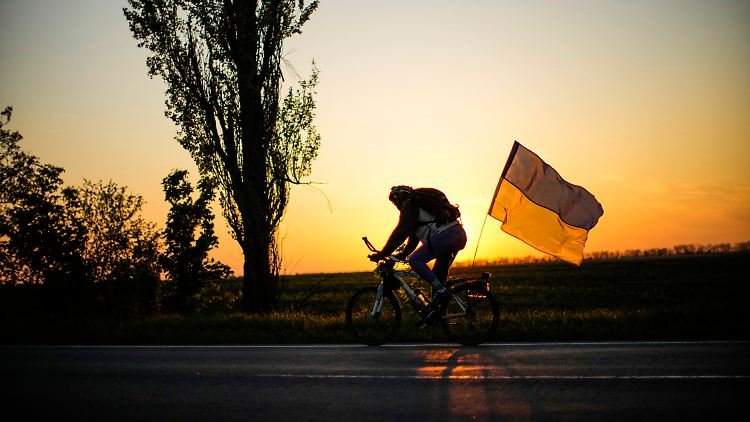 Ein Mann fährt mit einer ukrainischen Flagge auf der Straße zwischen Odesa und Mykolaiv im Süden der Ukraine.