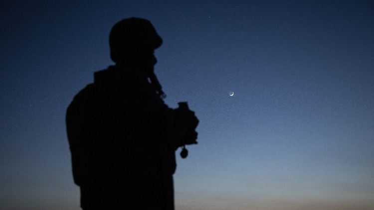 Ein ukrainischer Soldat beobachtet bei Einbruch der Nacht russische Stellungen.