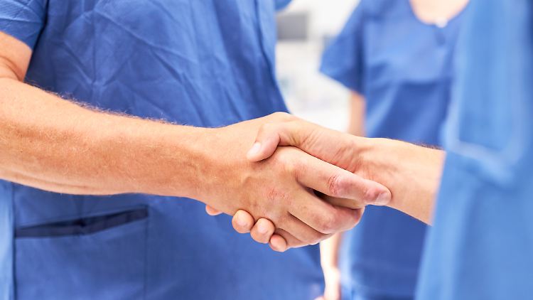 Selbst im Operationssaal versichert sich das Team per Handschlag der guten Zusammenarbeit.