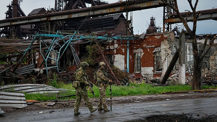 Russische Soldaten laufen durch das völlig zerstörte Mariupol.