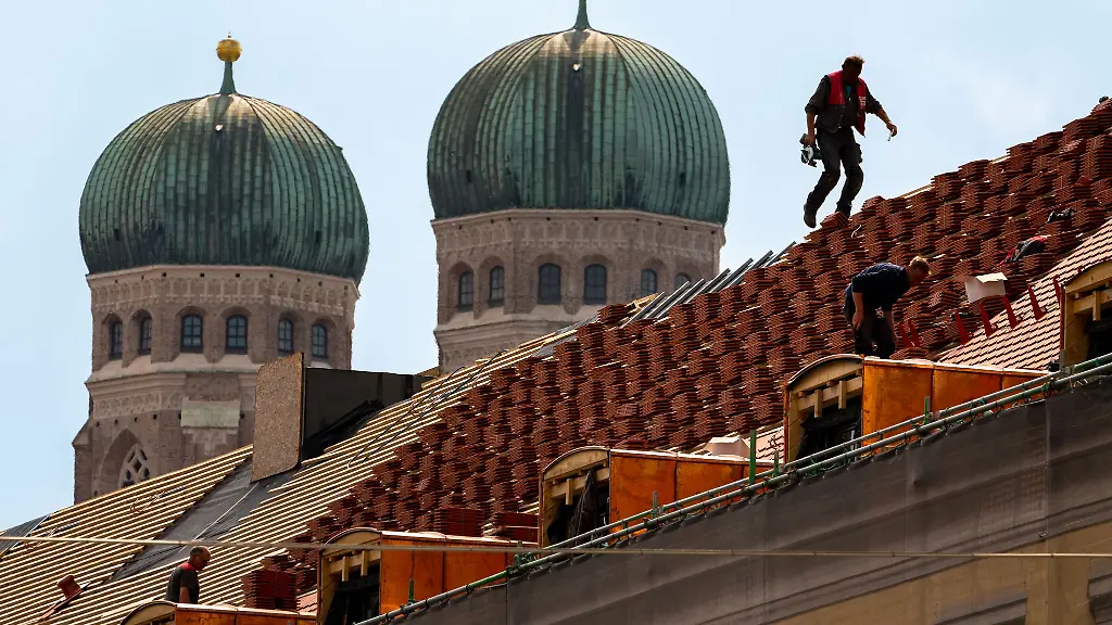 Dachdecker-auf-einem-Hausdach-vor-der-Kulisse-der-Muenchner-Frauenkirche