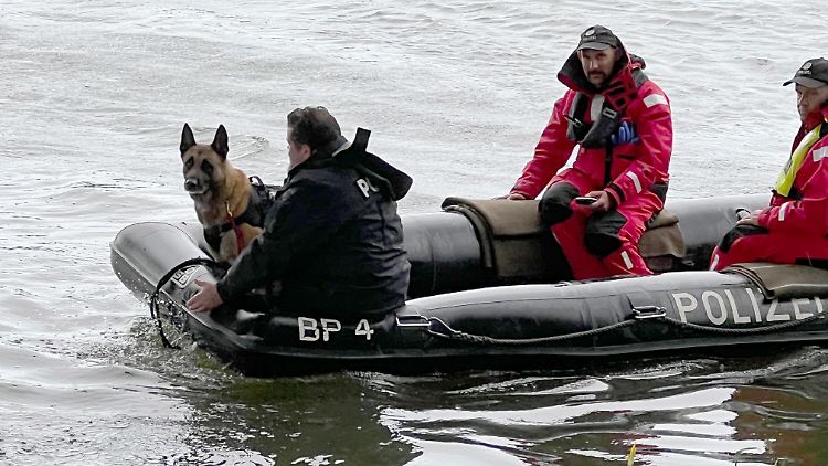 Einsatzkräfte fahren mit einem Boot der Polizei den Uferbereich der Donau ab.