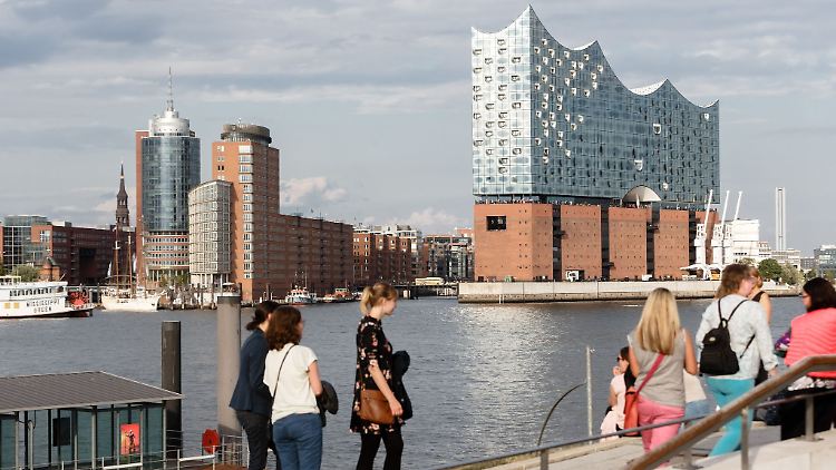 Touristinnen stehen am südlichen Elbufer am Anleger "König der Löwen" mit Blick auf die Elbphilharmonie.