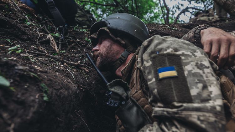 Ein ukrainischer Soldat schützt sich vor einem russischen Artellerieangriff.