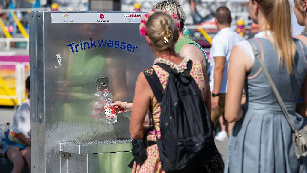 Eine-Frau-fuellt-ihre-Flasche-mit-kostenlosem-Trinkwasser-an-einem-Brunnen-auf