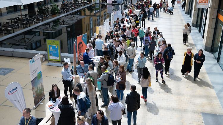 Besucher einer Jobmesse für ukrainische Geflüchtete stehen an Informationsständen.