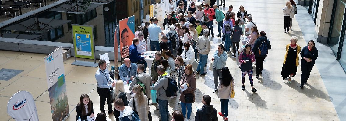 Besucher einer Jobmesse für ukrainische Geflüchtete stehen an Informationsständen.