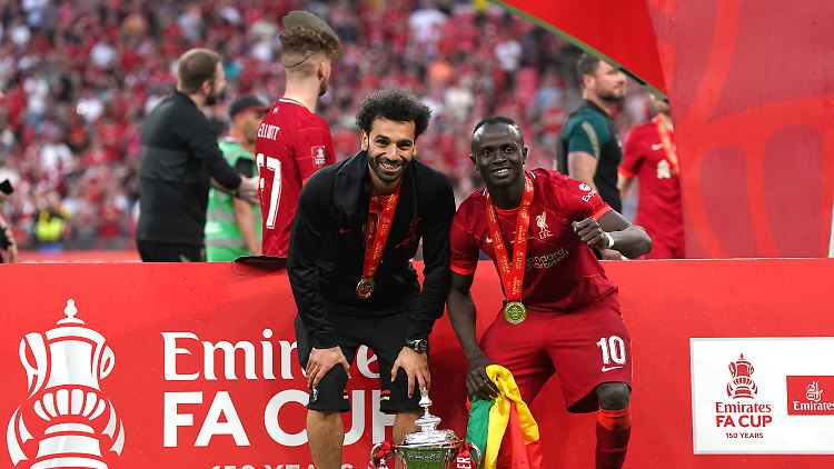 Mo Salah (l.) und Sadio Mané nach dem Gewinn des FA-Cups im Mai. Im Hintergrund hat jemand eine Maske über dem Kopf.