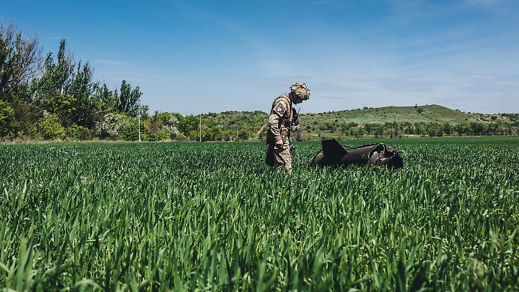 Ein ukrainischer Soldat nähert sich einer russischen Rakete, die auf ein Feld gestürzt ist.