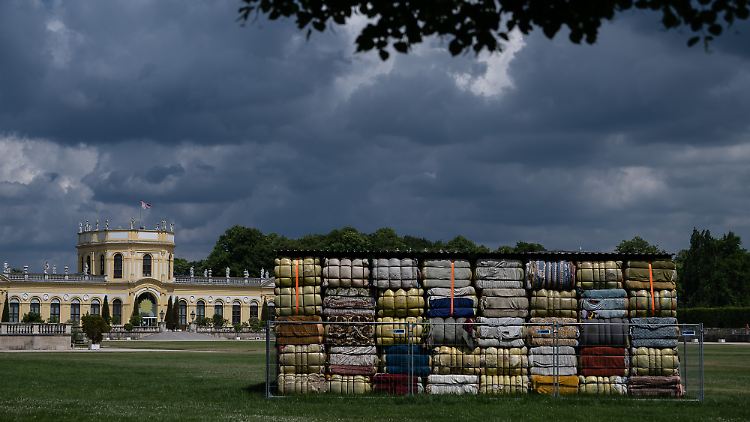 Ein Installation aus Altkleider-Ballen vom Nest Collective aus Nairobi steht umzäunt vor der Orangerie im Kasseler Staatspark Karlsaue.