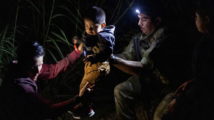 Einwanderer mit Kleinkind überqueren den Rio Grande an der texanischen Südgrenze der USA.