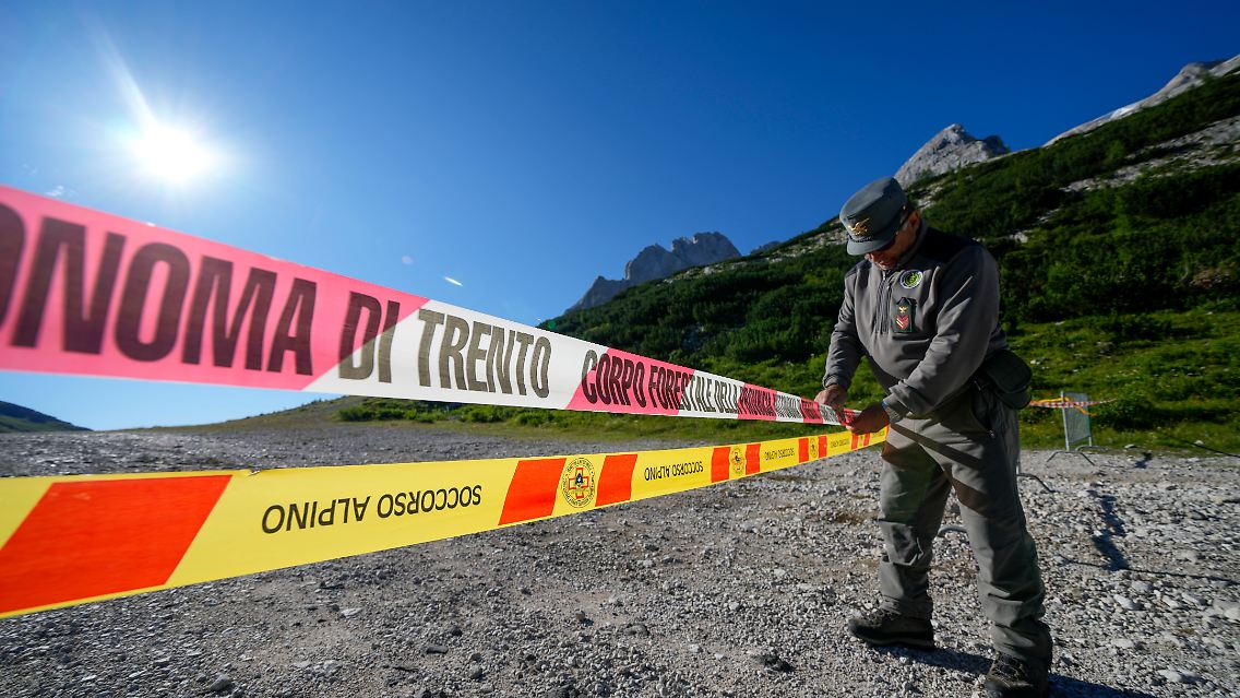Ein Beamter der italienischen Finanzpolizei blockiert den Zugang zum Marmolada-Berg und zum Punta-Rocca-Gletscher in den italienischen Alpen mit Absperrband.