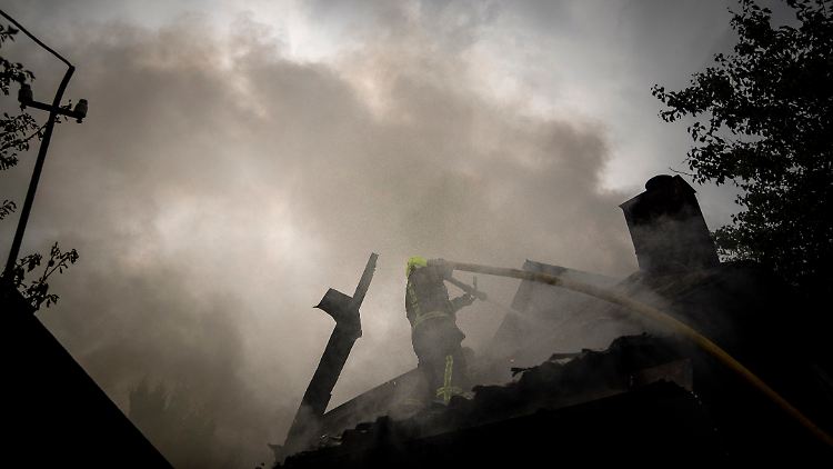 Ein Feuerwehrmann löscht das Feuer in einem zerstörten Haus nach einem russischen Angriff auf ein Wohnviertel in Charkiw.