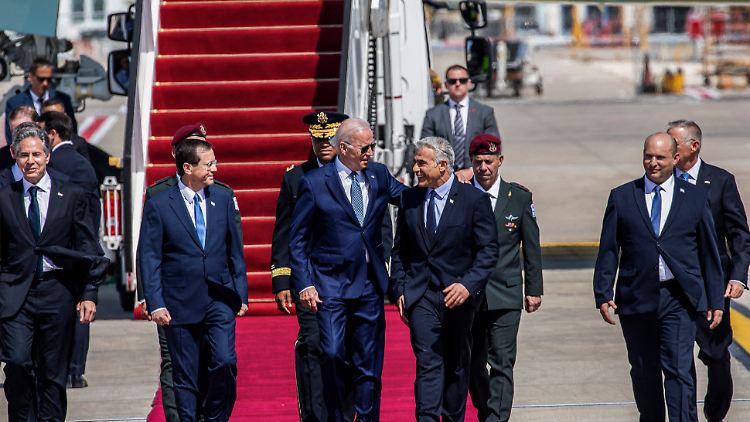 Am Ben-Gurion-Flughafen bei Tel Aviv läuft Biden zwischen dem israelischen Präsidenten Izchak Herzog und dem Ministerpräsidenten des Landes, Jair Lapid, um den er einen Arm legt.