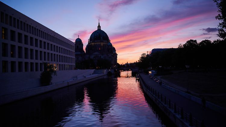 Nach einem warmen Sommertag färbt die untergegangene Sonne den Himmel über dem Berliner Dom rötlich.