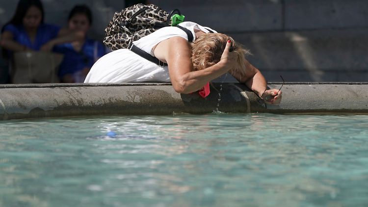 Eine Frau erfrischt sich am Brunnen am Trafalgar Square.