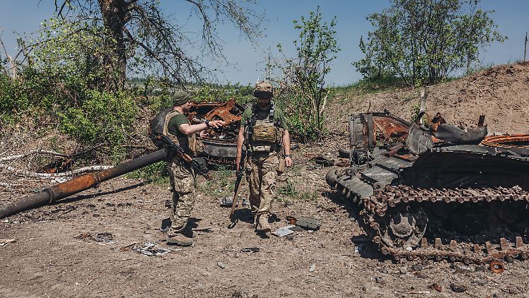 Ukrainische Soldaten neben einem russischen Panzerwrack. 