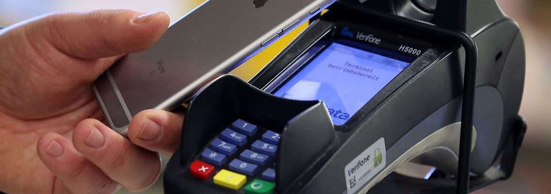 Ein Mann bezahlt mit seinem Smartphone kontaktlos in einem Supermarkt.