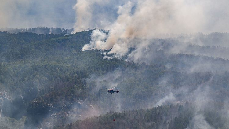 Ein Lastenhubschrauber aus Österreich fliegt mit einem Löschwasser-Außenlastbehälter, um den Waldbrand im Nationalpark Sächsische Schweiz zu löschen. 