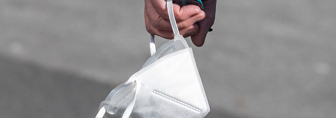 Ein Passant trägt eine FFP2-Maske in der Hand.