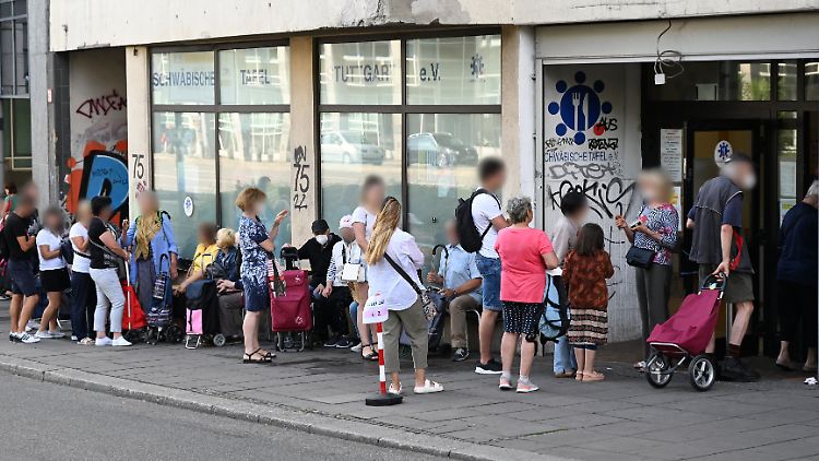 Menschen stehen vor einer Ausgabestelle der Tafel Schlange.