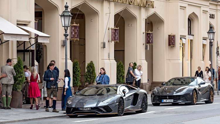 Teure Supersportwagen mit deutschem Kennzeichen stehen vor einem Münchener Luxushotel.