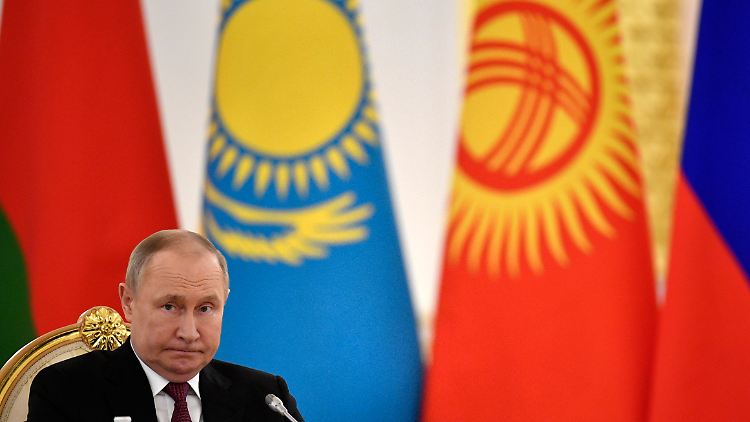 Russlands Präsident Wladimir Putin sitzt bei einem Treffen des Militärbündnisses OVKS vor den Flaggen Kasachstans und Kirgisistans.