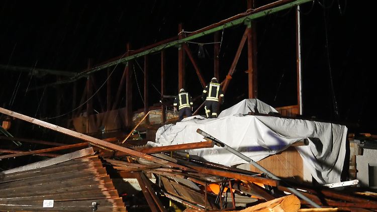 Feuerwehrleute sichern die Überreste einer Lagerhalle.