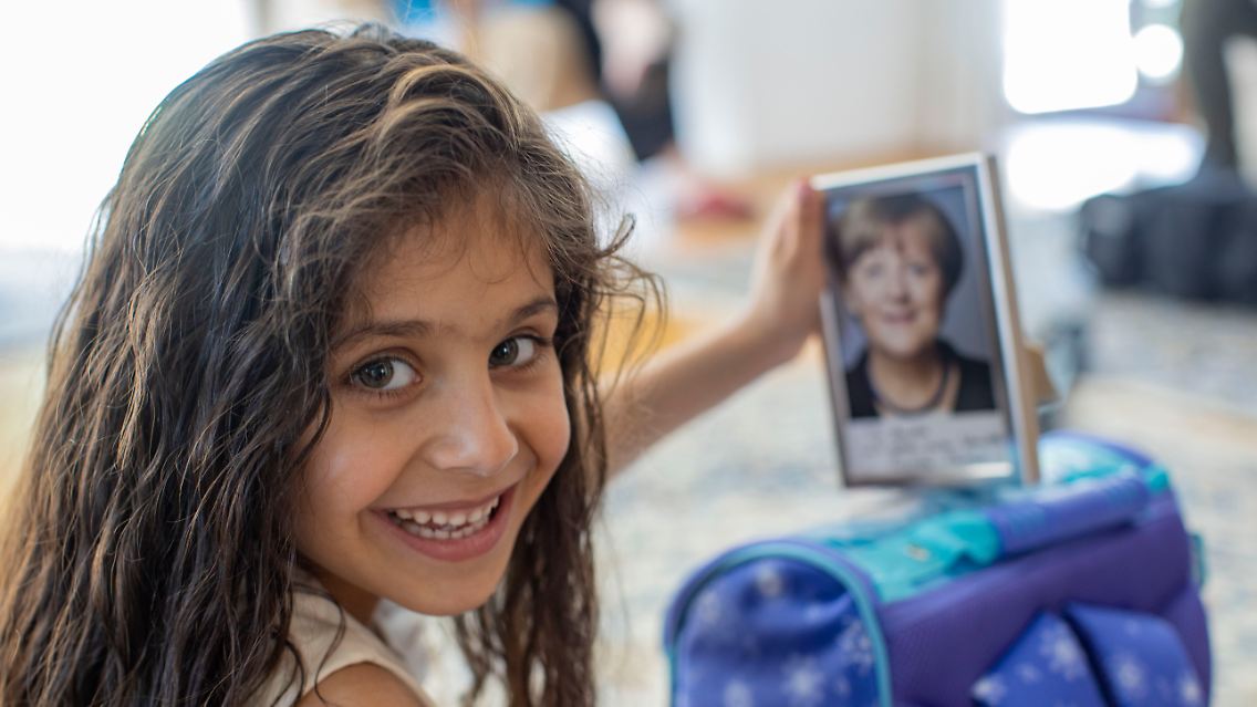 Angela hält ein Bild von Ex-Bundeskanzlerin Merkel mit einem Gruß "Für Angela" und der Unterschrift von Merkel.