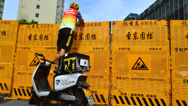 Auf der Ferieninsel Hainan lässt sich ein Kurier nicht davon abhalten, trotz einer Barrikade eine Bestelllung auszuliefern.