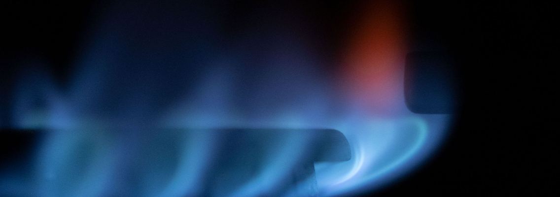 Blau-schimmernde Gas-Flämmchen sind an einem Gasherd zu sehen.