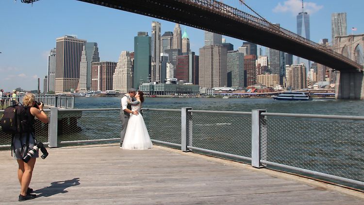 Ein Kuss fürs Erinnerungsfoto: Das Brautpaar Annika Heisig und Patrick Brosch am New Yorker Pebble Beach im Brooklyn Bridge Park, im Hintergrund die Skyline von Manhattan.
