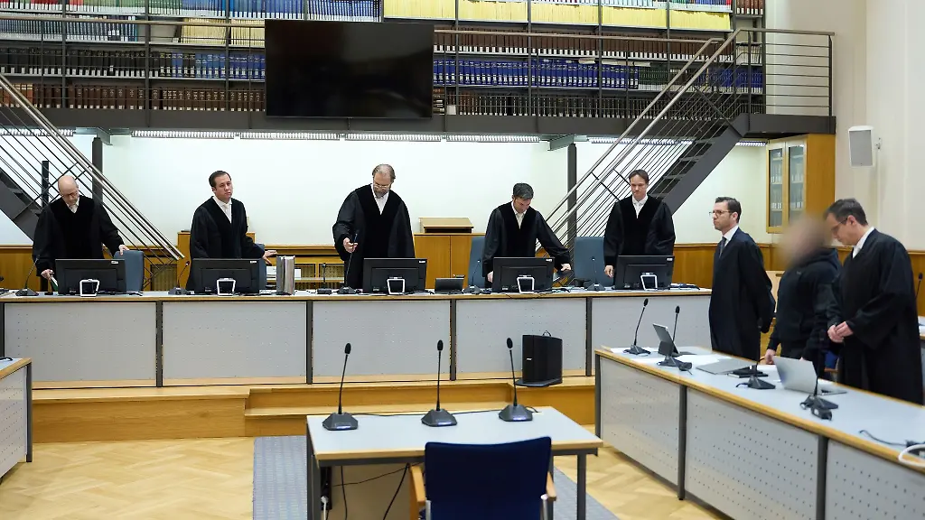 Der-Senat-der-Angeklagte-und-seine-Verteidiger-stehen-im-Gerichtssaal-des-Oberlandesgerichts