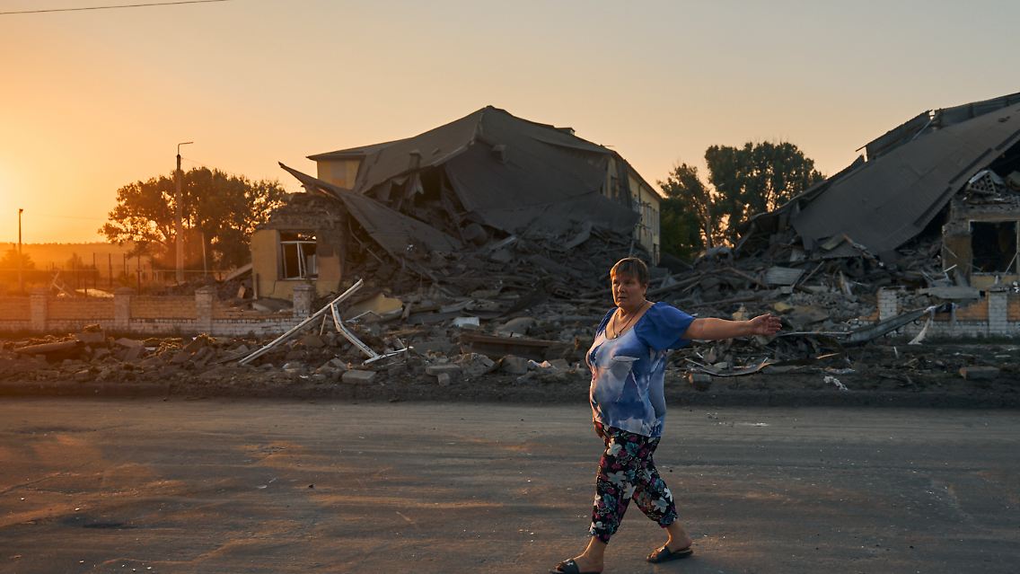 Eine Frau geht an einer Schule in der Region Donezk vorbei, die bei einem russischen Angriff zerstört wurde.