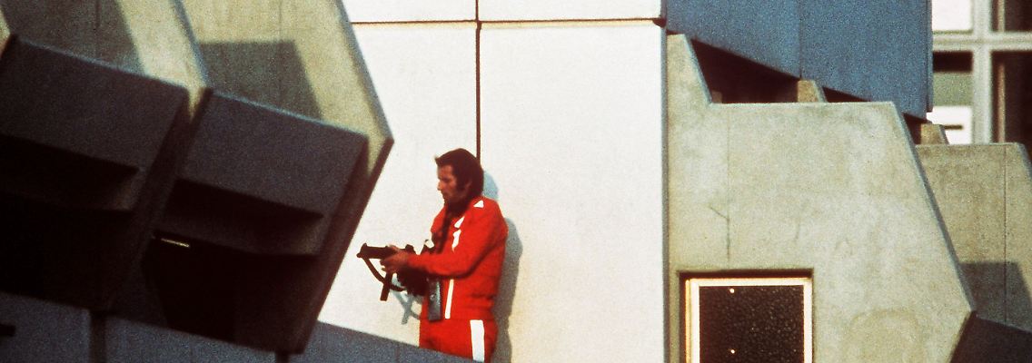 Ein bewaffneter Polizeibeamter im Trainingsanzug sichert am 05.09.1972 im Olympischen Dorf in München den Block, wo Terroristen die israelischen Geiseln festhalten.
