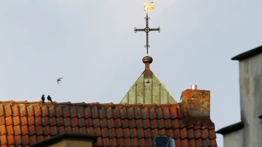 Ein-Kreuz-vom-katholischen-Dom-St-Petrus-ist-im-Licht-der-untergehenden-Sonne-zu-sehen