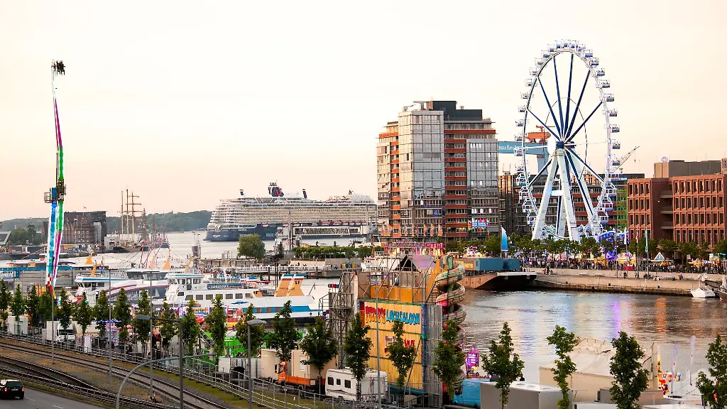 Ein-Riesenrad-dreht-sich-bei-der-Kieler-Woche-2024-Im-Hintergrund-faehrt-das-Kreuzfahrtschiff-Mein-Schiff-7